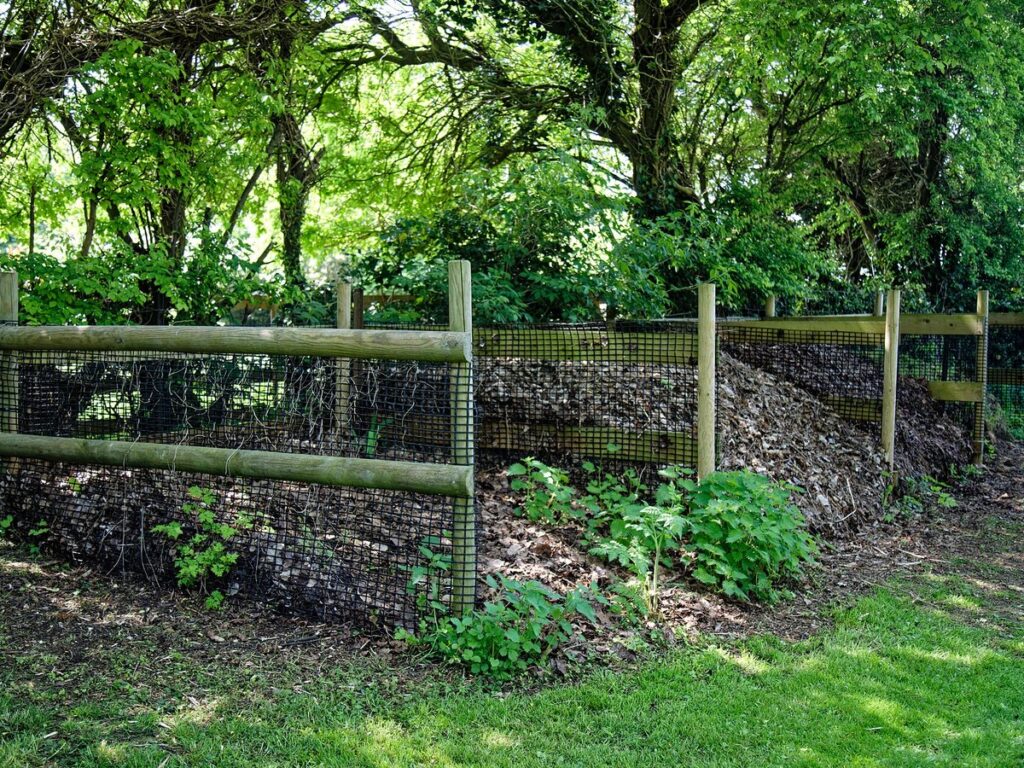 Komposthaufen aus Holzlatten im Garten mit Küchen- und Gartenabfällen